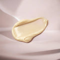 Close-up of a smooth, beige cream smear on a soft pink background