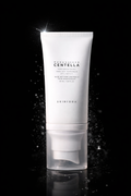 Skin1004 Madagascar Centella Tone up Sunscreen in a white tube on a black background.