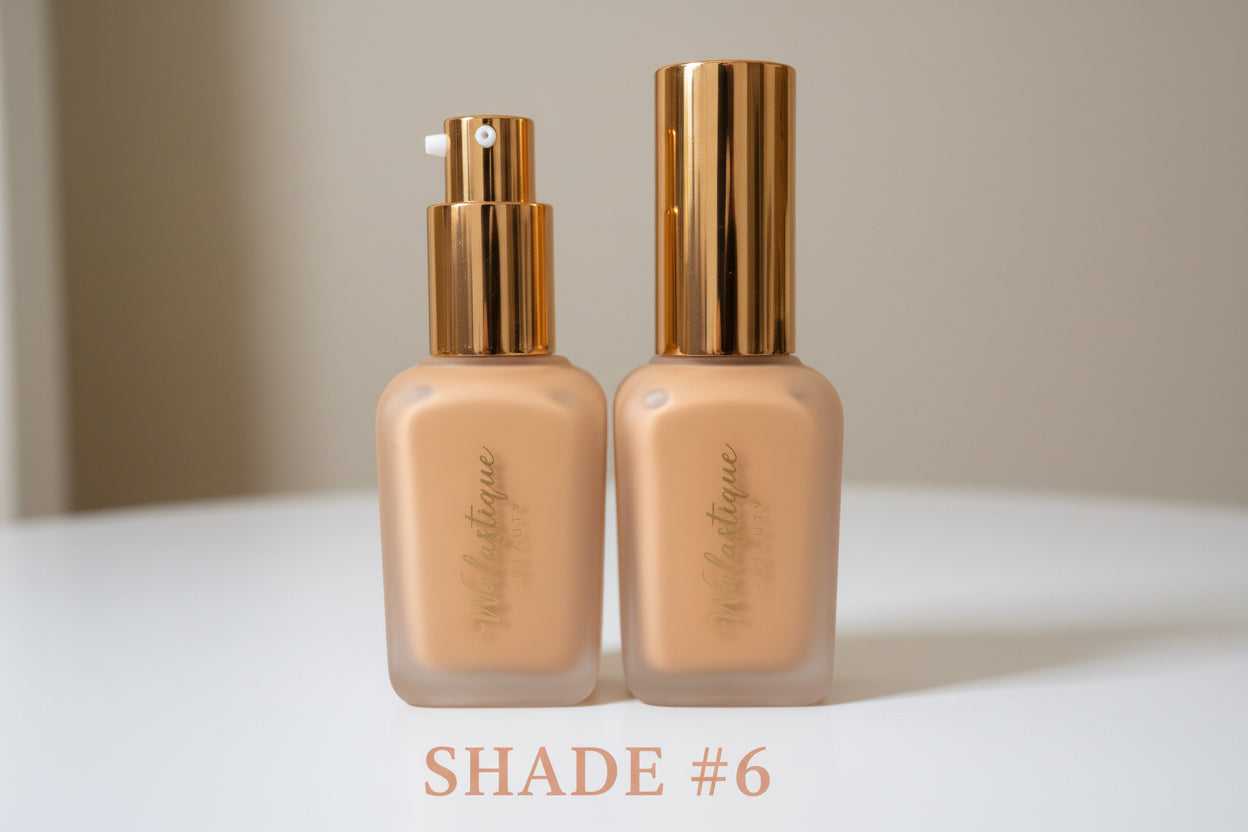 Two Walastique Beauty Foundation bottles with gold caps on a light surface.