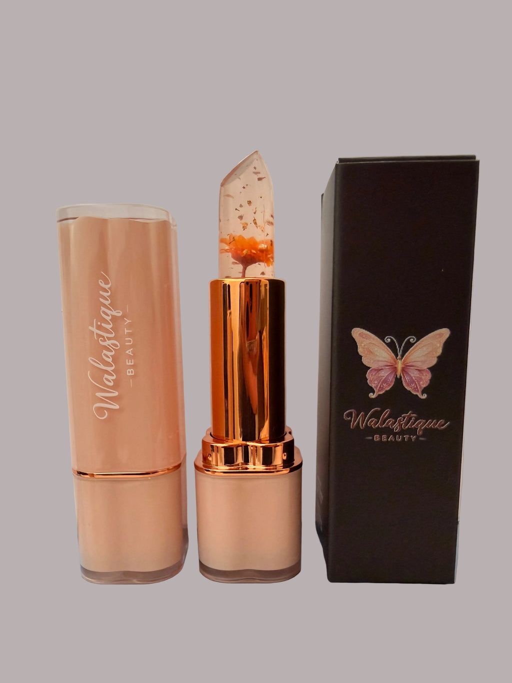 Walastique Beauty Clear lipstick with orange flower and a packaging box on a light grey background.