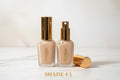 Two foundation bottles of Walastique Beauty  with gold caps on white background.