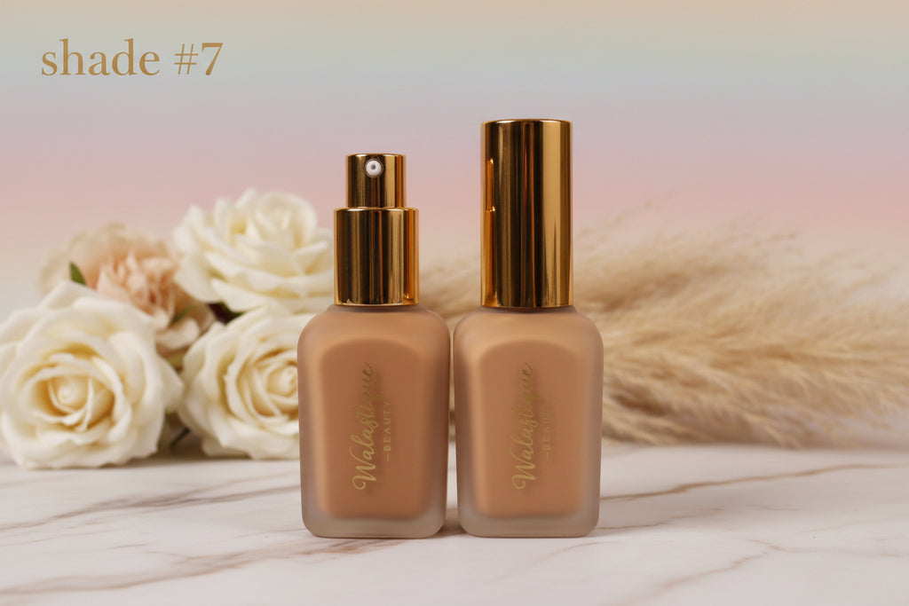 Two bottles of Walasitique foundation shade #7 with gold caps on white flower background