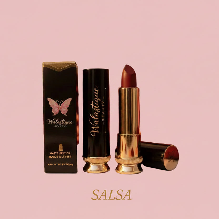 Walastique Beauty matte lipstick in Salsa shade, warm red tone with gold tube and packaging on a pink background