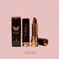 Walastique Beauty matte lipstick in Salsa shade, warm red tone with gold tube and packaging on a pink background